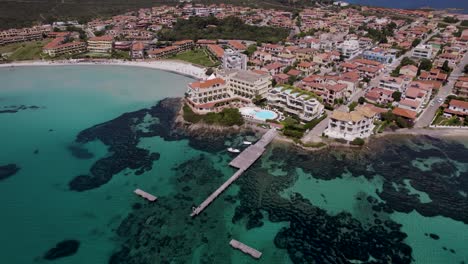 Vista-Aérea-De-La-Ciudad-Costera-Con-Muelle,-Bahía-Tropical-Del-Mar-Tirreno,-Cerdeña