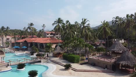 Aerial-rises-from-resort-hotel-swimming-pool-over-sunny-palm-trees