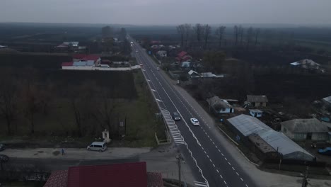 Vehículos-Que-Pasan-Por-Una-Carretera-Asfaltada-Con-Casas-Al-Lado-En-El-Condado-De-Vrancea,-Rumania---Vista-Aérea