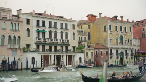 Traditional-Gondola-Boats-Sailing-In-Front-Of-Palazzo-Sernagiotto,-Cannaregio-On-The-Grand-Canal-In-Venice,-Italy