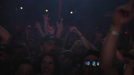 Multitud-De-Personas-Bailando-En-Un-Festival-De-Música-Rock-Con-El-Símbolo-De-Una-Roca-En-La-Mano