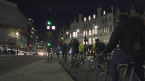 Group-of-cyclists-Wait-For-Green-Signal-at-City-Crosswalk-During-Night,-London