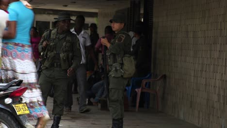 Militares-Colombianos-De-Pie-En-Una-Acera-Concurrida-Sosteniendo-Rifles-Mientras-Pasan-Civiles