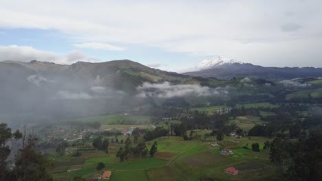 Foggy-and-cloudy-valley-landscape-with-small-houses-in-aerial-drone-view