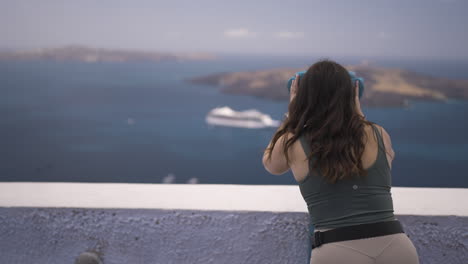 Toma-En-Cámara-Lenta-De-Un-Turista-Que-Mira-A-Través-De-Binoculares-La-Ciudad-De-Santorini