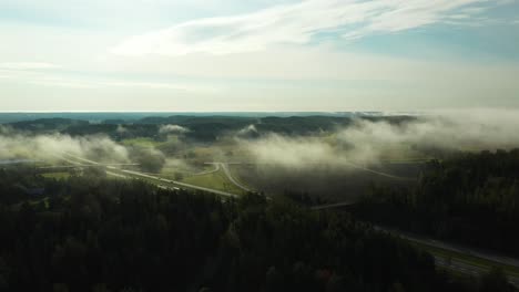 Forward-moving-aerial-view-of-morning-fog-floating-over-a-4-lane-highway-with-cars-and-trucks