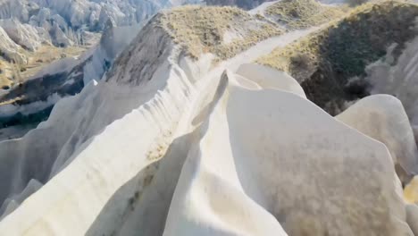 slow-motion-60-fps-drone-footage-of-valley-in-Cappadocia-turkey-midday-sunny-beautiful-landscape-with-pointy-rocks-and-big-mountains-textures-colors