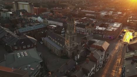 pigeons-folk-fly-over-peaceful-Yorkshire-town-at-early-morning-golden-sunrise,-scenic-aerial