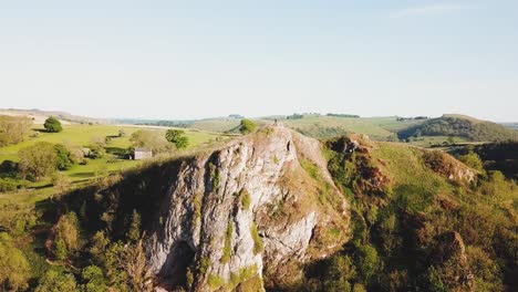 Toma-Aérea-Con-Dron-Alejándose-De-La-Cueva-De-Thor,-Ashbourne,-Peak-District-Al-Atardecer