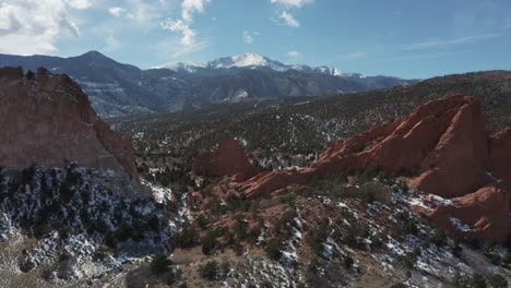 Aerial-pan-up-reveal-shot-of-Pikes-Peak-with-red-rocks-in-foreground