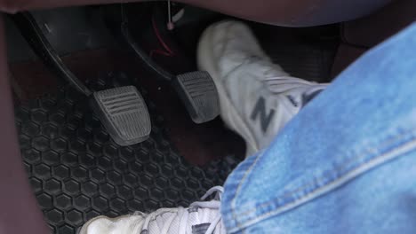 A-mans-feet-seen-working-the-gas,-brake,-and-clutch-pedal-in-a-vehicle