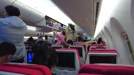 Chinese-people-inside-aircraft-removing-hand-luggage-in-cabin-Beijing-Capital-airport-during-Covid-19-pandemic