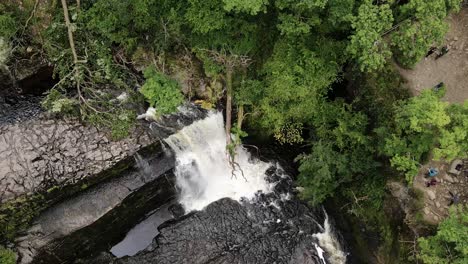 Vista-Aérea-Que-Se-Eleva-Sobre-La-Idílica-Cascada-Del-Bosque-Galés-Sin-Cultivar-De-Breacon-Beacons