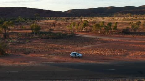 Vista-Aérea-En-órbita-De-Un-Automóvil-En-Una-Carretera-Cerca-De-Alice-Springs-Temprano-En-La-Mañana,-Territorio-Del-Norte,-Australia