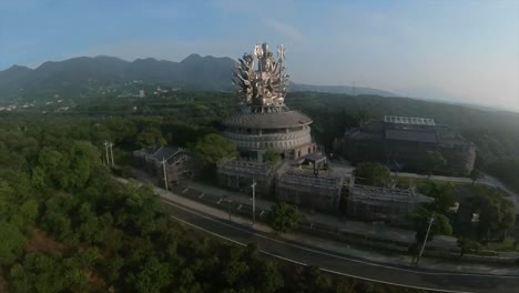 Toma-Aérea-En-órbita-De-Una-Enorme-Estatua-Plateada-De-La-Diosa-Guanyin-En-China-Con-Muchos-Brazos-Y-Dos-Cetros