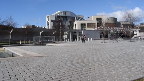 Couple-walk-across-the-courtyard-to-the-front-of-the-Scottish-Parliament-building