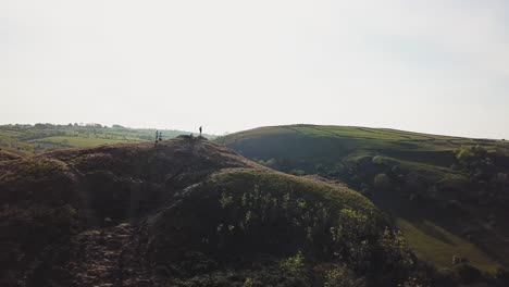 Toma-Aérea-De-Un-Dron-Volando-En-El-Sentido-De-Las-Agujas-Del-Reloj-Alrededor-De-Personas-Paradas-En-La-Cima-De-Mam-Tor,-Castleton,-Peak-District,-Inglaterra