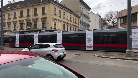 Tram-in-Vienna-moves-from-right-to-left-and-stops-at-the-station,-Austria,-Europe,-following-shot-from-the-side