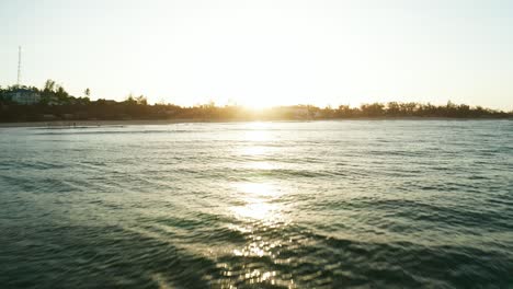 Drone-shot-heading-towards-the-sunset-over-the-shoreline-of-Tofo,-Mozambique