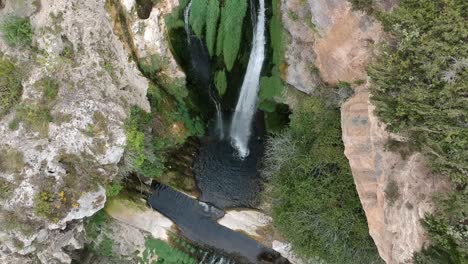 Aerial-views-of-a-waterfall-with-a-cave-and-an-old-building-in-Catalonia,-Spain