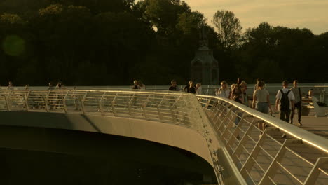 Toma-Panorámica-A-Contraluz-De-Personas-Caminando-Por-El-Puente-De-Cristal-En-Kiev-En-Una-Cálida-Tarde-De-Otoño