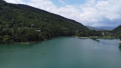 Vista-Aérea-A-Baja-Altura-De-Los-Bosques-De-Montaña-Que-Se-Encuentran-Con-El-Lago-Limpio-De-Paltinu-En-El-Valle-De-Doftana-En-Rumania