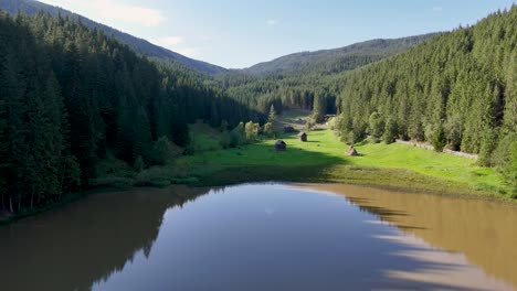 Gradual-aerial-unveiling-of-Iezer-Lake,-nestled-amidst-the-dense-greenery-of-Sadova-in-the-Bucovina-region-of-Romania