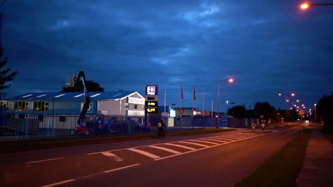 Man-on-a-bicycle-rides-on-an-empty-road-next-to-a-gas-station-at-night-in-Dundalk-,-Ireland