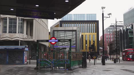 London---Empty-Streets---Tottenham-Court-Road-Underground-Station-closed-with-masked-pedestrians-and-buses-passing