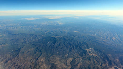 Volando-Sobre-Terreno-Montañoso,-Cielo-Despejado,-Atmósfera-Azul.