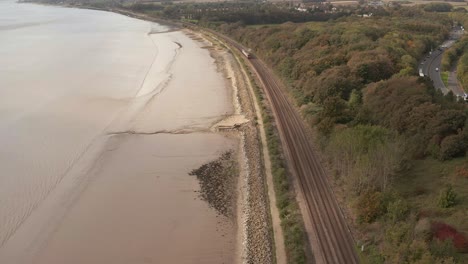 Standbildaufnahme-Eines-Zuges,-Der-Entlang-Von-Bahngleisen-Fährt,-Mit-Küstenlinie-Und-Autobahn-Auf-Beiden-Seiten