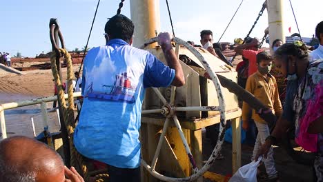 Un-Trabajador-En-Un-Transbordador-Girando-Una-Gran-Rueda-De-Un-Cabrestante-Del-Barco-E-Intentando,-Un-Trabajador-O-Marinero-Indio-Cerrando-El-Cabrestante-Del-Barco-Con-Una-Gran-Rueda-En-Un-Barco-Lleno-De-Pasajeros-Y-Viajeros