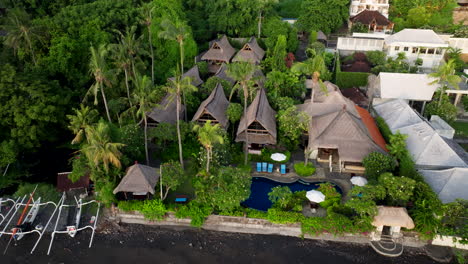 Vista-Aérea-De-Un-Hotel-Boutique-Relajado-A-Lo-Largo-De-La-Playa-De-Amed-Con-Piscina-Al-Aire-Libre-Y-Un-Exuberante-Paisaje-Verde-En-Bali