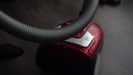 Man-uses-foot-switch-to-turn-on-canister-vacuum-on-laminate-floor