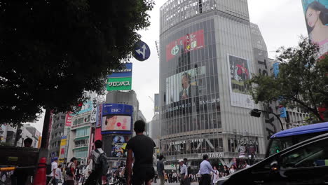 Los-Peatones-Cruzan-Durante-El-Día-El-Famoso-Y-Concurrido-Paso-De-Peatones-De-Shibuya-En-Tokio-Mientras-El-Tráfico-Y-Los-Ciclistas-Esperan.