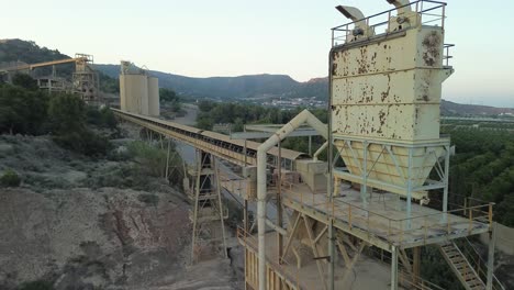 Cantera-Industrial-Con-Cintas-Transportadoras-Y-Trituradora-De-Piedra-En-Medio-De-Colinas,-Que-Muestra-Maquinaria-Pesada-Y-Operaciones-Mineras.