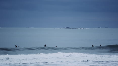 Silhouetten-Von-Vielen-Menschen,-Die-Spaß-Beim-Surfen-Auf-Dem-Atlantik-An-Einem-Bewölkten-Tag-Haben