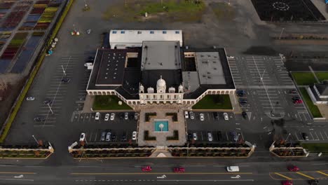 Drone-4K-of-front-facade-of-Sikh-temple-with-beautiful-and-elaborate-sculpture-and-symmetrical-architecture-revealing-the-blueberry-farmland-and-parking-lots-around-the-building