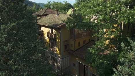 Villa-Amarilla-Abandonada-Rodeada-De-árboles-En-Italia,-Escondida-En-Un-Frondoso-Bosque