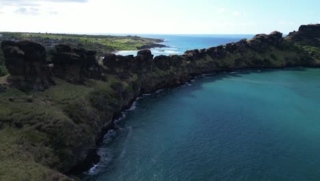 Aerial-view-of-dramatic-coastal-cliffs-and-a-deep-blue-bay-on-a-tropical-island