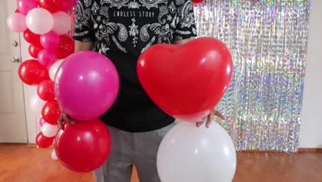 Man-tying-together-Valentines-day-party-balloons-in-decorated-room