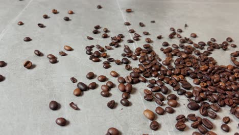 Scattered-roasted-coffee-beans-on-a-flat-surface,-showcasing-their-rich-brown-tones-and-natural-textures