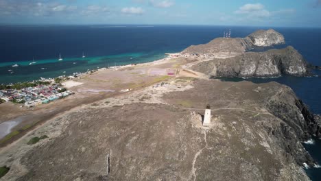 Gran-roque-island-with-its-lighthouse-and-village,-surrounded-by-the-blue-sea,-aerial-view