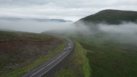 Aerial-view-of-a-car-driving-through-foggy-mountains-along-the-Ring-Road-in-Iceland-during-summer