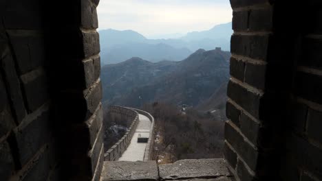 Experience-a-captivating-slow-motion-reveal-capturing-the-stunning-landscape-from-a-window-along-the-Great-Wall-of-China,-showcasing-its-ancient-beauty-and-the-surrounding-mountains