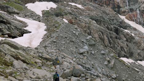 A-lone-hiker-ascends-the-rugged,-rocky-terrain-of-Fellaria-Glacier-in-the-Valmalenco-Alps,-surrounded-by-dramatic-mountain-landscapes