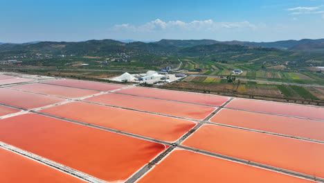 Aerial-view-rotating-backwards-over-salt-production-pools,-sunny-day-in-Albania