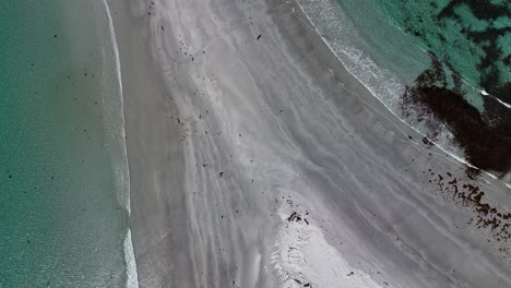 Closeup-shot-of-white-sand-and-black-sand-on-a-sandbar-at-beach,-aerial-top-down