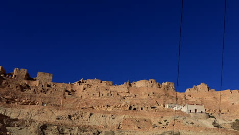 Antiguas-Estructuras-De-Ksar-Bajo-Un-Cielo-Azul-Vibrante-En-El-Accidentado-Paisaje-De-Túnez