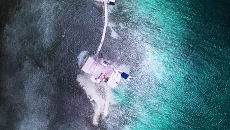 A-palafito-above-turquoise-waters-in-los-roques,-showing-a-stunning-coastline,-aerial-view